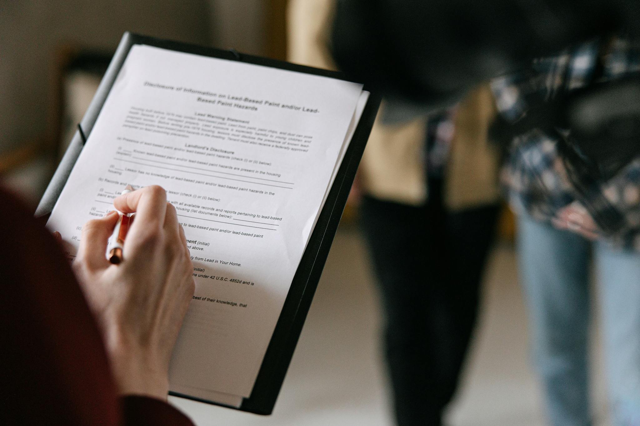 A couple examines real estate documents indoors with focus on writing and discussion.